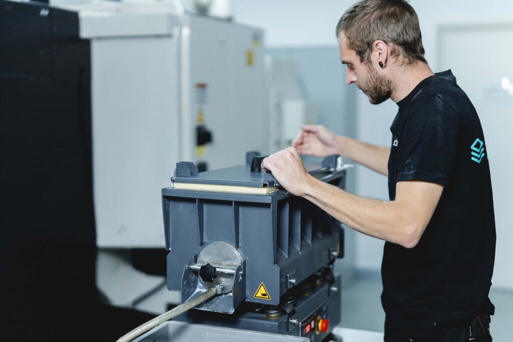 Ein Mitarbeiter von prioadd verschließt den Deckel einer Gleitschleifmaschine, nachdem diese befüllt hat.