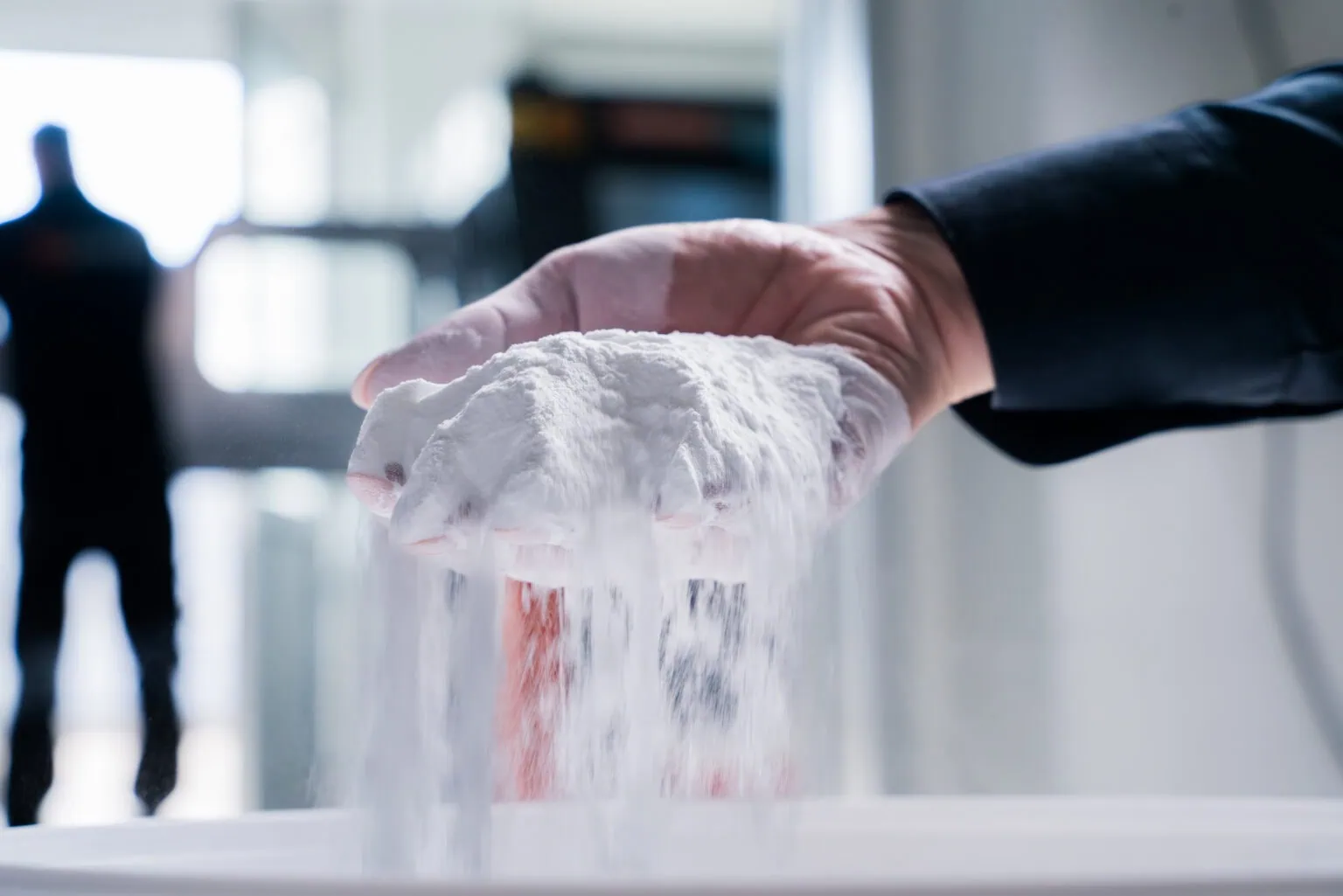 Un employé de prioadd tient dans sa main de la poudre plastique blanche pour impression 3D SLS.