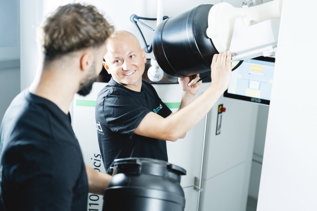 Two employees replenish the material on an EOS P110 SLS system.