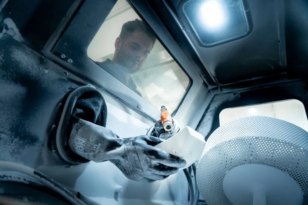 Un collaborateur de prioadd projette des billes de plastique sur un composant fabriqué de manière additive.